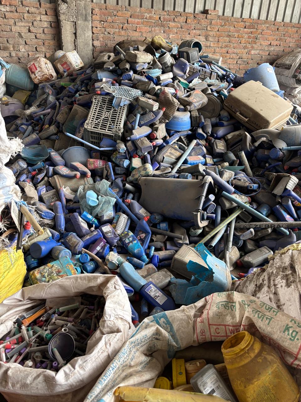 Large pile of collected plastic bottles and crates at a recovery facility